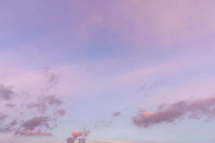 A view of clouds in a sky during dusk is displayed