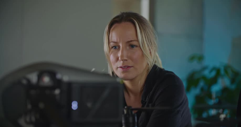 Woman talks to coworker while she examines machine as they sit in office