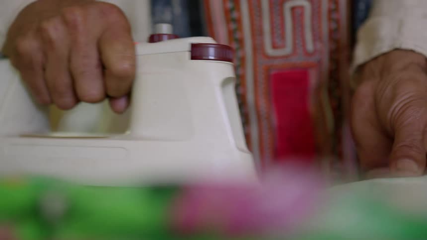 An up close of a person using a fabric iron to smooth fabric