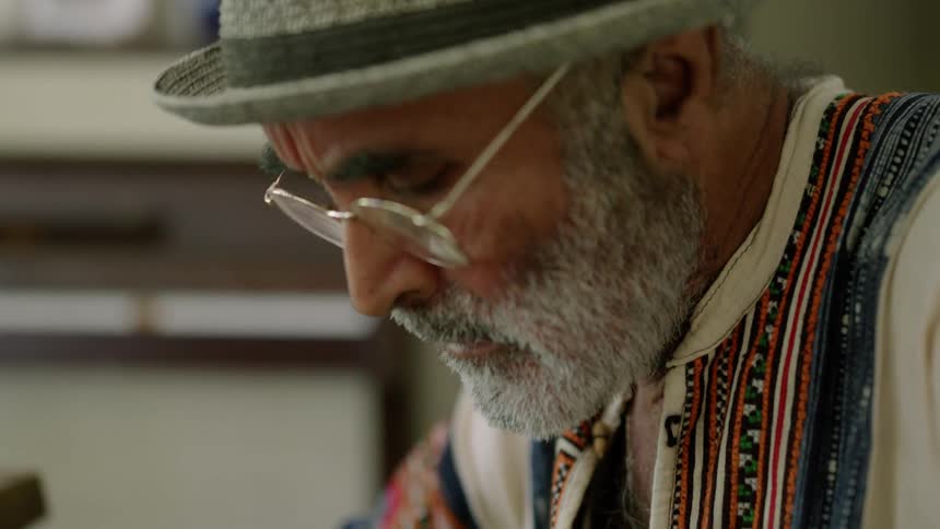 Older bearded man considers while sitting outside