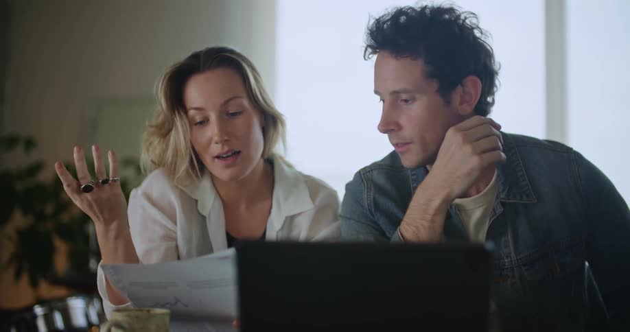 Man and woman are indoors and using a laptop to go over finances