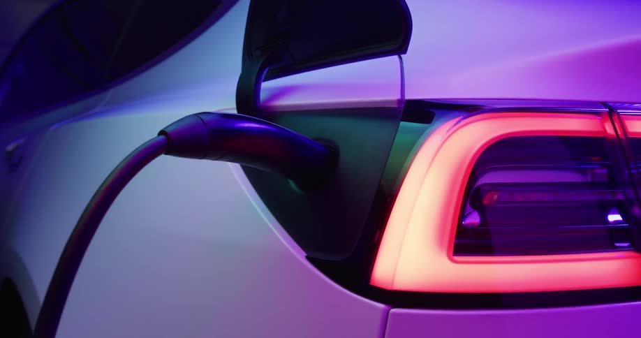 Close up of the charging port of an electric vehicle under shifting colorful lights
