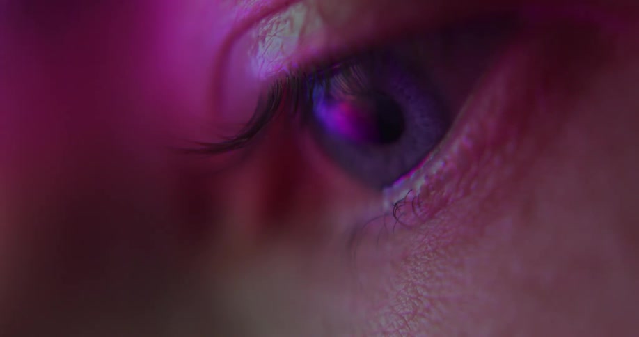An extreme close up of a persons eye staring down as light reflects off it