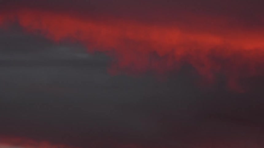 A red tinted cloud rolling into a dark sky