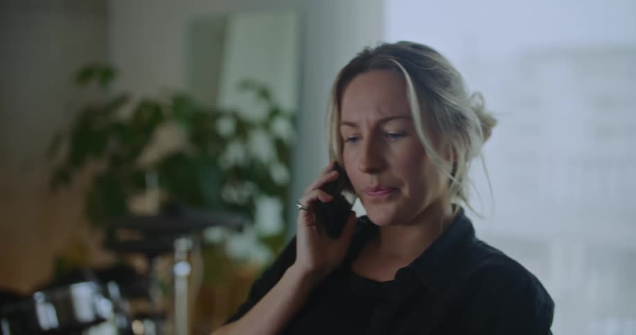 A woman is talking on her cell phone and sitting indoors