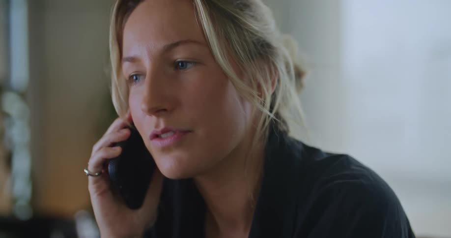 A woman has a lively conversation on a cell phone while sitting indoors