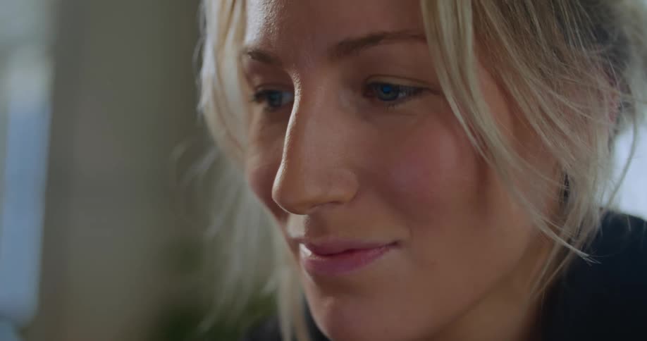 Blonde woman smiles while watching screen