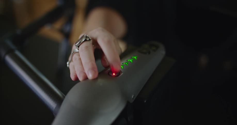 Close up of the hand of a woman pressing the red turn on button on a drone