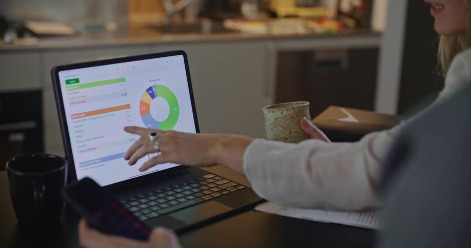 Coworkers sit in office discussing data on laptop screen