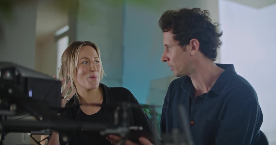 Two people on a room have a lively conversation while configuring a drone over a table