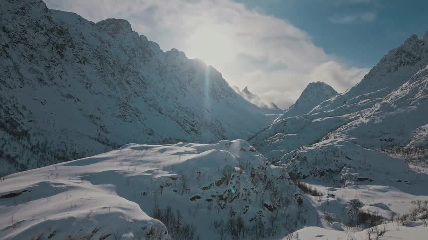 An aerial view of a snowcovered mountain range and valley during a sunny winter day