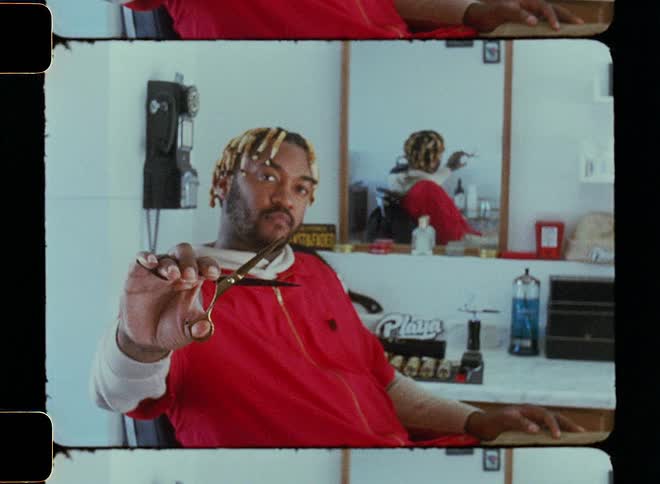 Male hairdresser sits in barber chair holding a pair of hair scissors