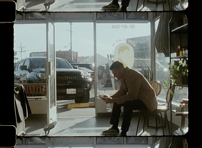 A young man is sitting down and reading something on his phone