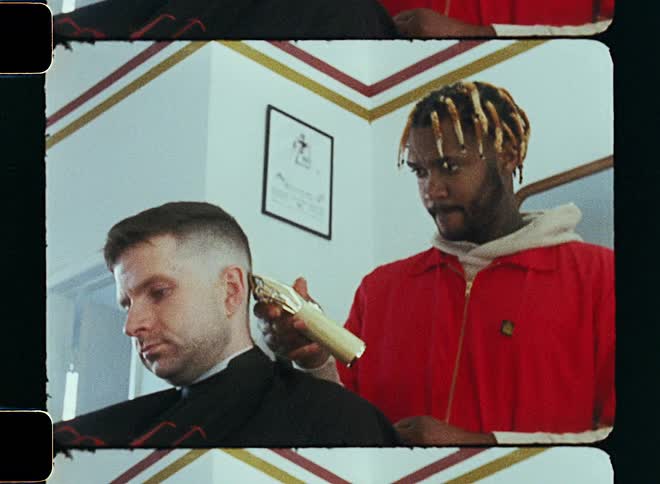 A barber is cutting someones hair at the barber shop