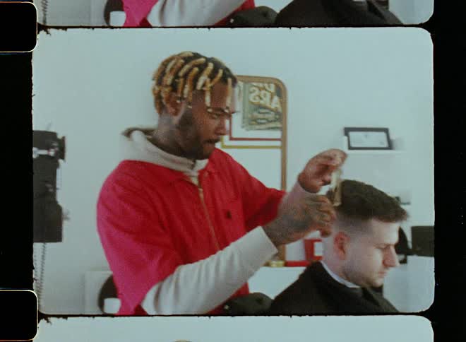 A man is cutting someones hair at the barber shop