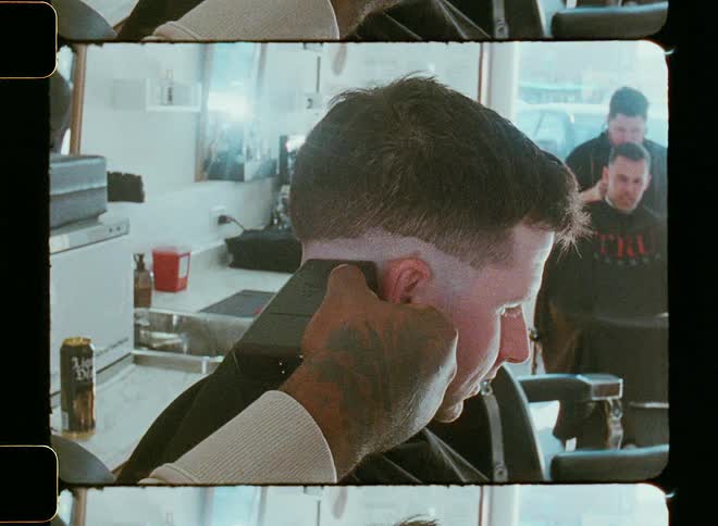 Barber neatens haircut on client sitting in barber chair