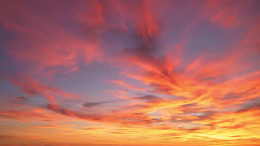 Sunlight shines on clouds and reflect color as they move across the sky and grow deeper and darker as the sun sets
