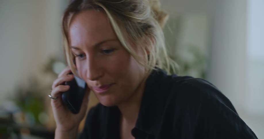 A woman is smiling and talking on her cellphone