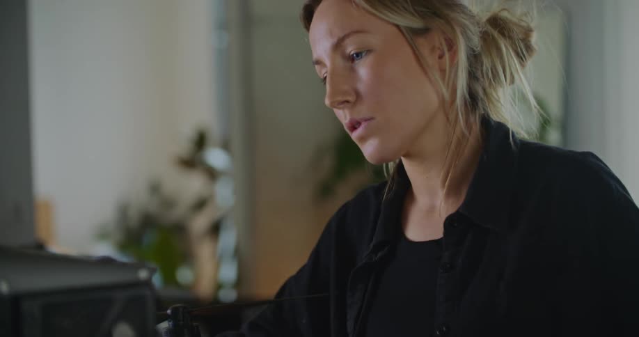 A young woman is indoors and looking at the video camera