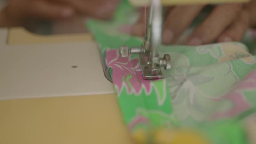 A person is using the sewing machine on some clothes