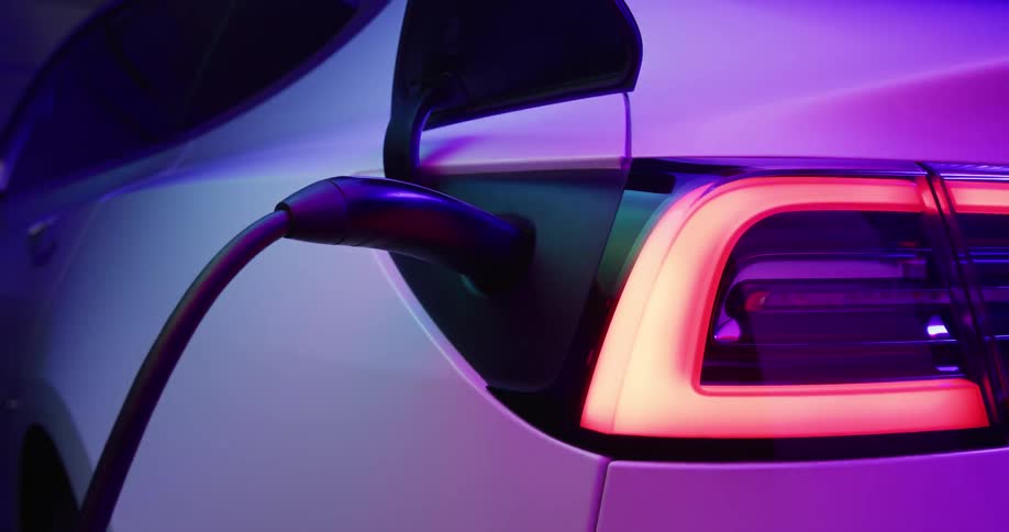 Close up of the charger on an electric vehicle under shifting colorful lights
