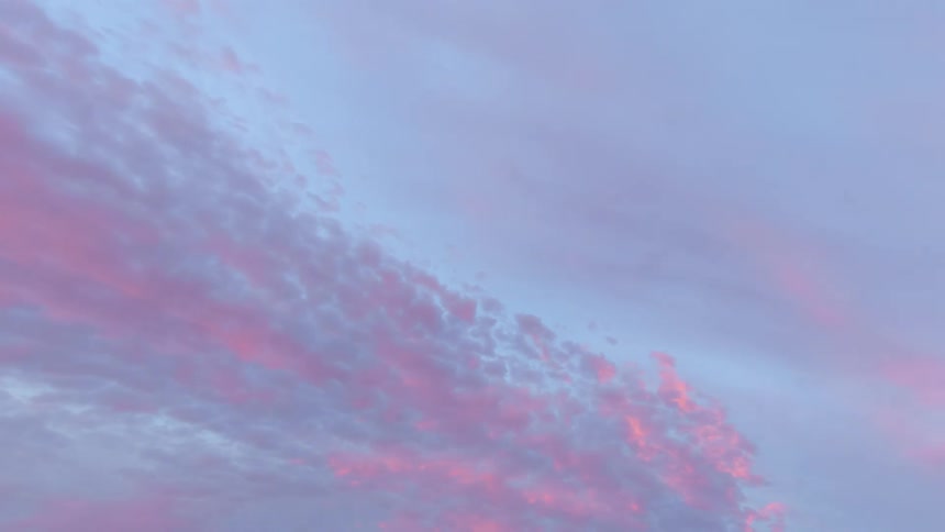 Clouds move across the sky and reflect sunlight as the colors change and the sky turns dark as the sun sets
