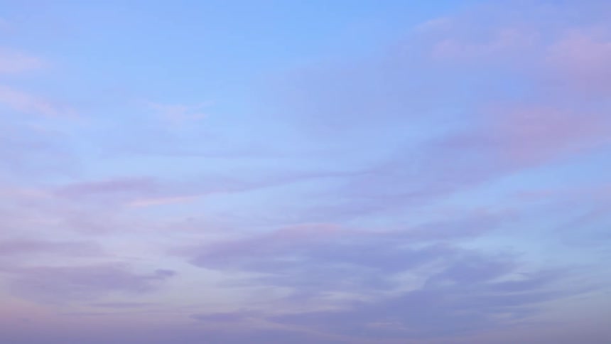 A time lapse view of a cloudy sky transitioning from day to dusk at sunset