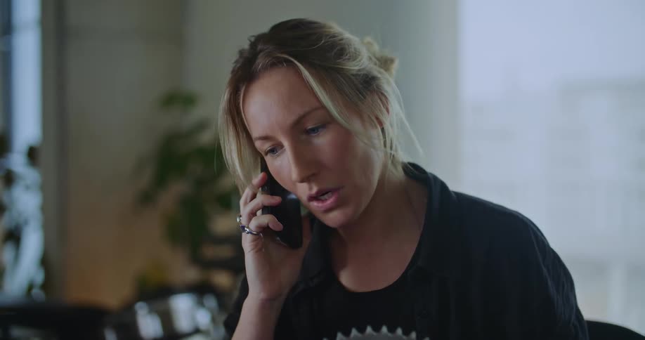 Woman examines large metal gear while standing in office on phone call