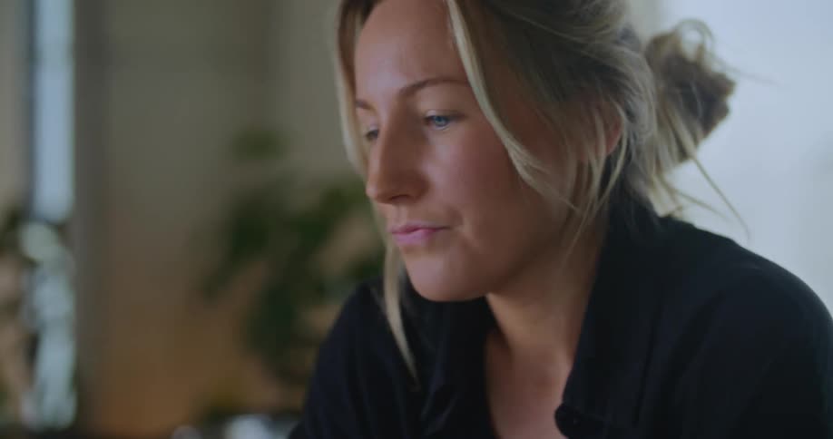 A woman is typing on a laptop computer and she stops to think and then continues to type