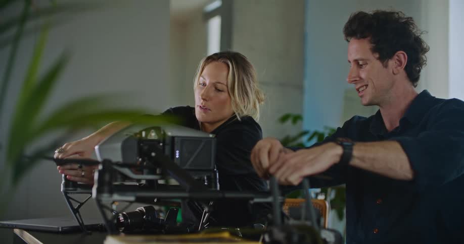 A man and woman standing next to each other putting a piece of equipment together