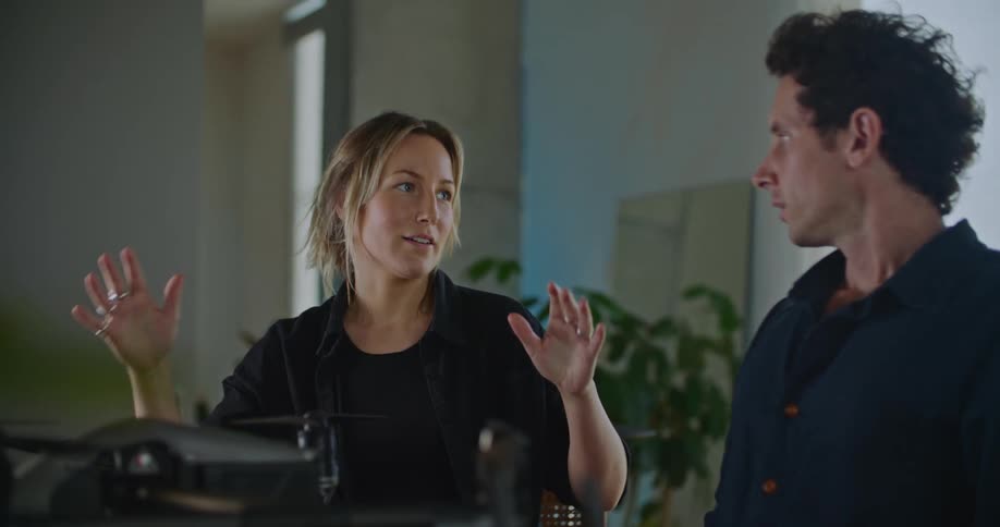 A man and woman sitting next to each other conversing as the man adjusts equipment in front of them