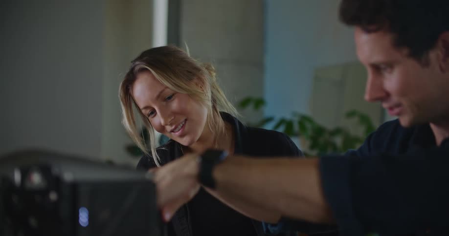 Coworkers high five after successfully adjusting machine in office