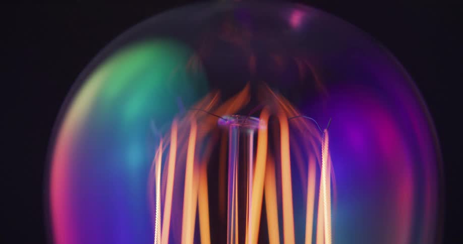 A close up of a light bulb with the inner part turning on then off and lights reflecting off the bulb