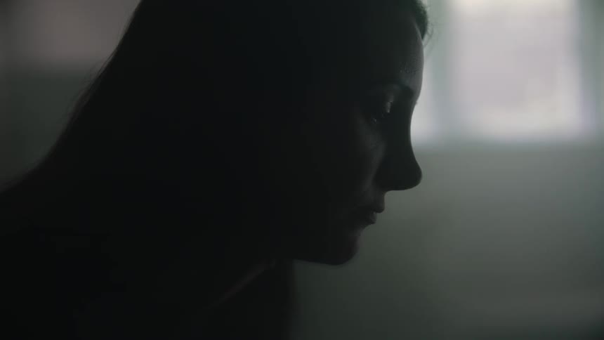 Close up of a man sitting on a dimly lit room looking at another person