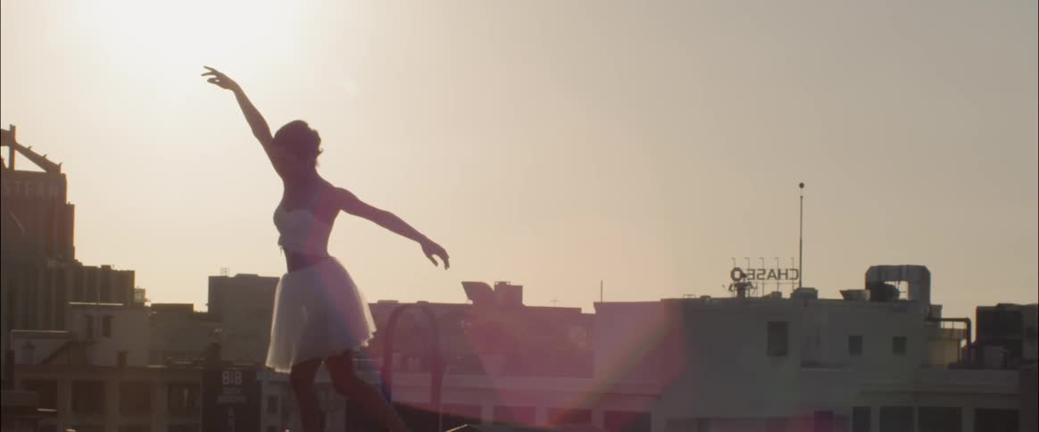 Woman is dancing ballet on rooftop in city