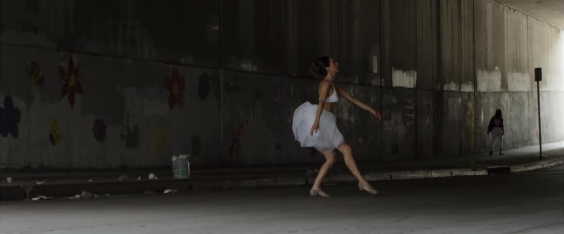 A ballet dancer leaps into the air on the street