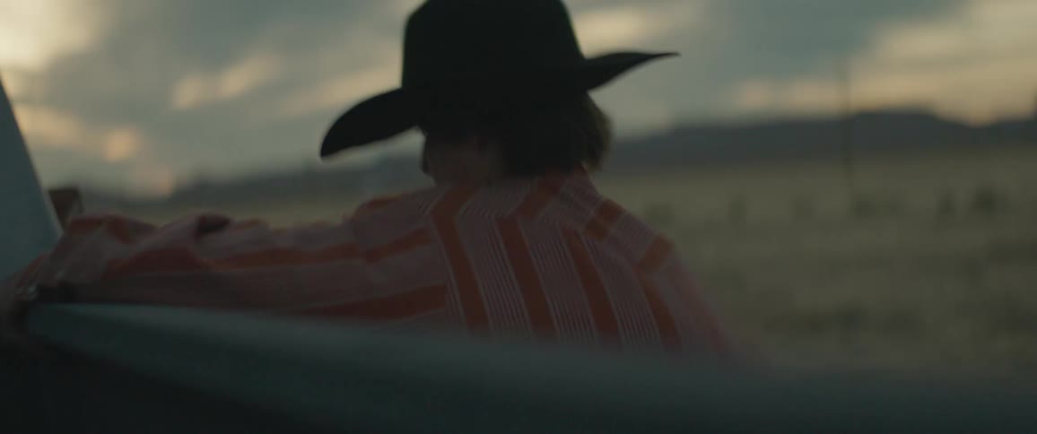 A man frantically unloads a bag into the back of a pickup truck and enters