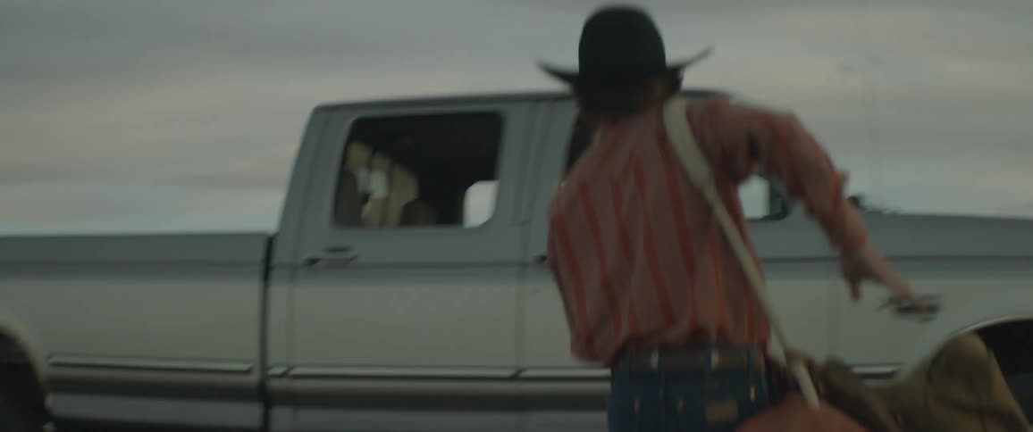 Modern cowboy getting picked up after putting his bag in the bed of a truck on a cloudy day