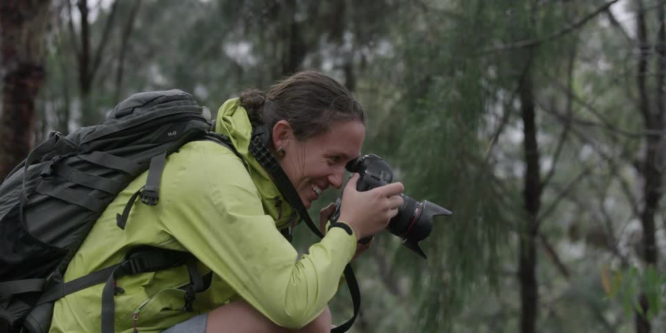 A female photographer focuses her camera and smiles