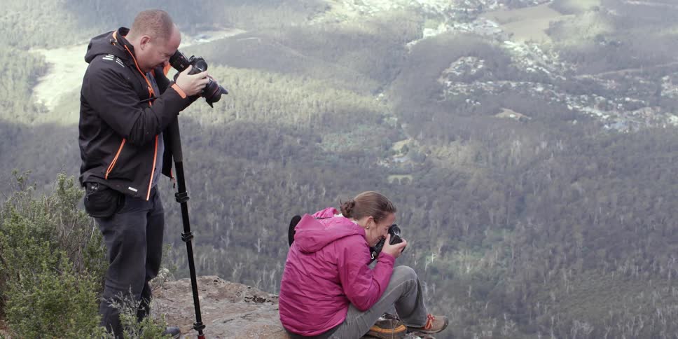 Man and woman film mountains in nature