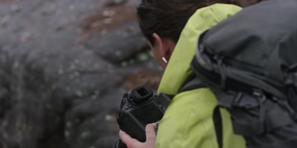 A woman takes photographs near some rocks
