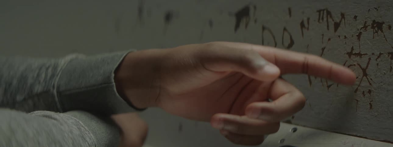 A person scratches paint off of a wall