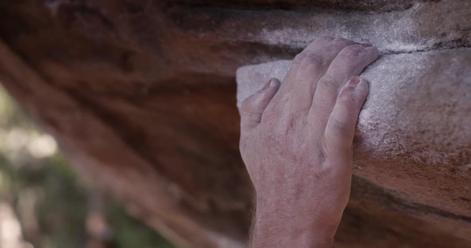 A hand grabs on a rock climbing up