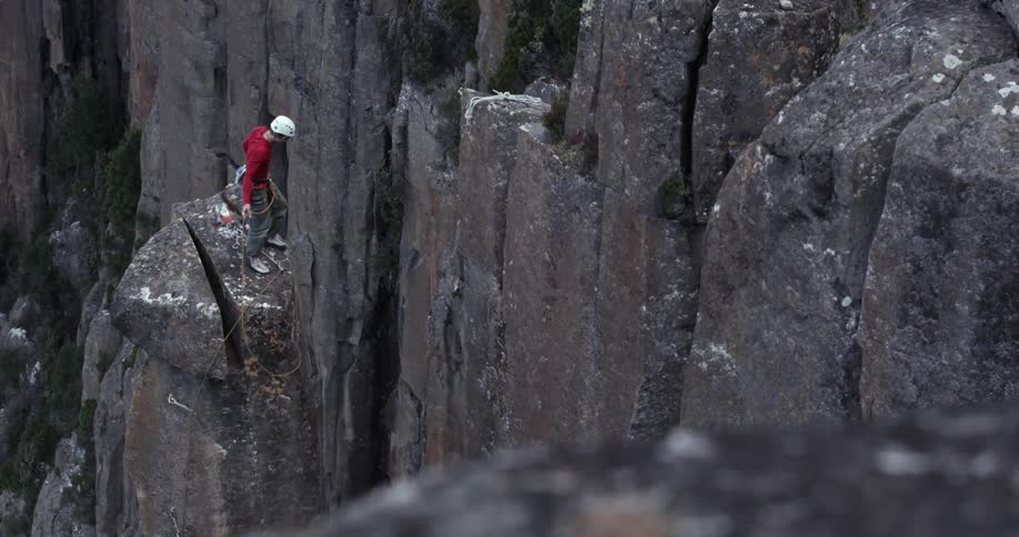 A man climbs the side of a steep mountain