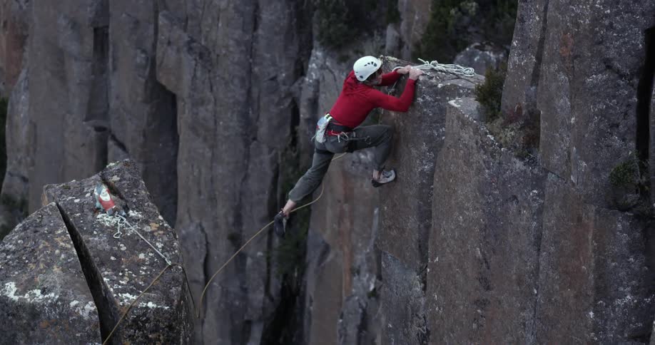 A man in red jumps from one ledge to another