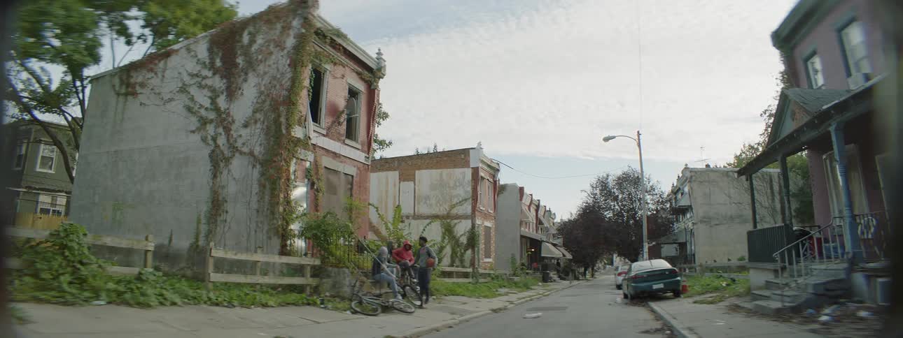 A teenager bounces a basketball in a run down neighborhood