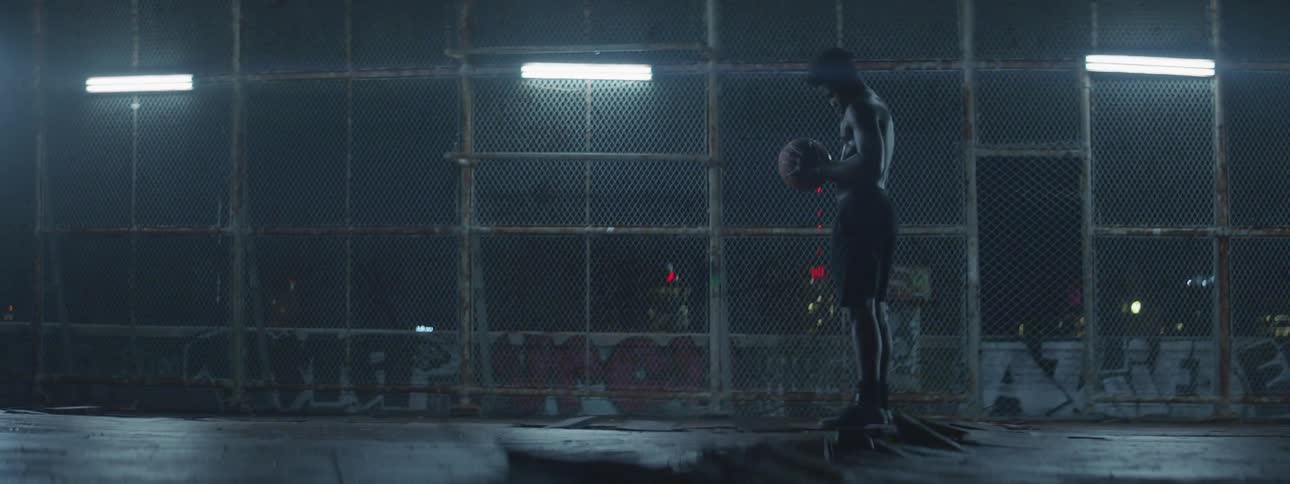 A man is holding a basketball in a dark court