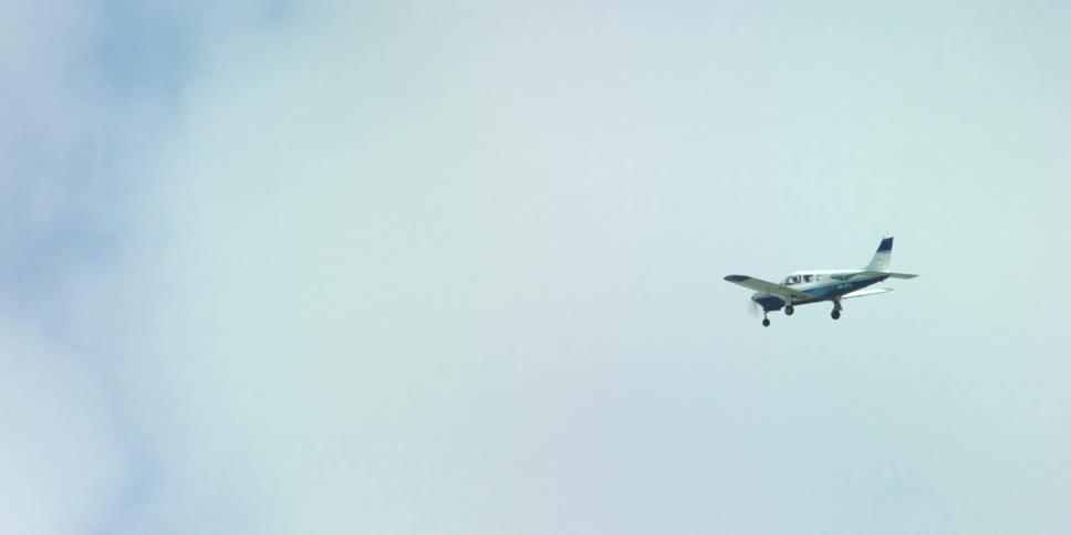 A small airplane flies in the air on a cloudy day