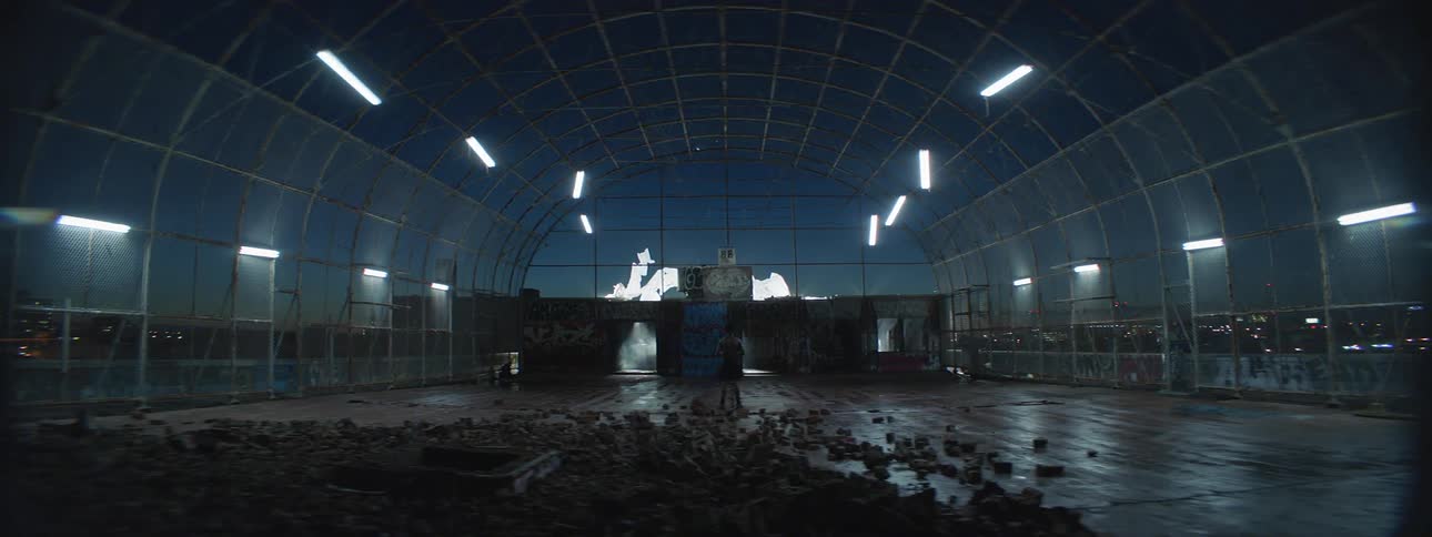 A person stands in a dirty domed clear building as fireworks go off outside