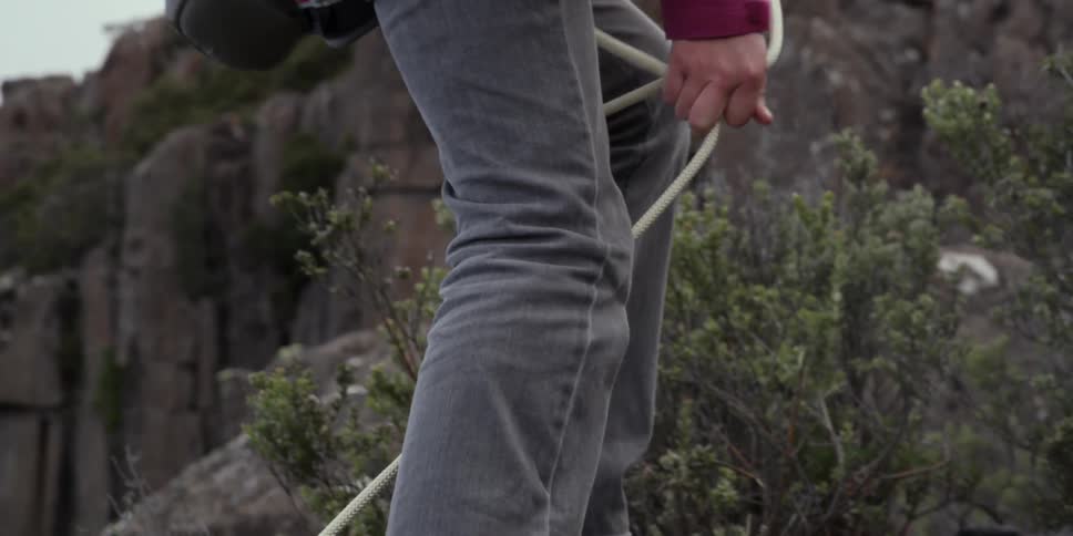 A man is climbing over rocks with a rope